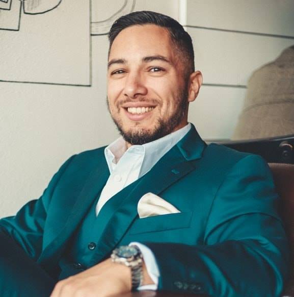 Adam Rodriguez smiling in a suit